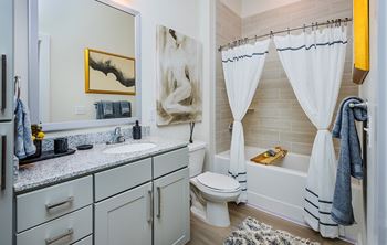 A bathroom with a white toilet, a sink, a bathtub, and a mirror.